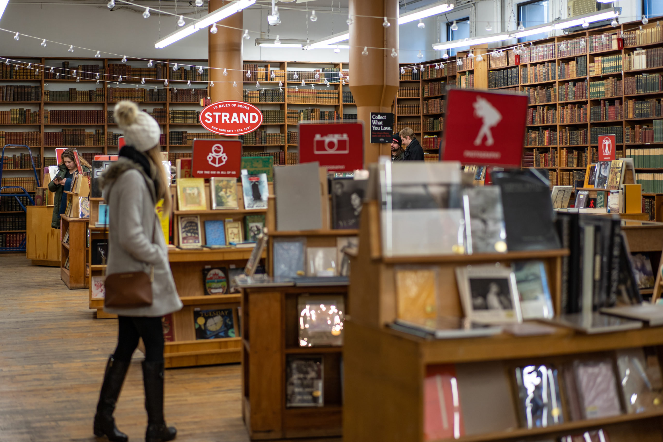 Top Two Boroughs for Bookworms: Independent Bookshop, The Strand, wooden bookshelves, and a woman in a hat and coat walking through