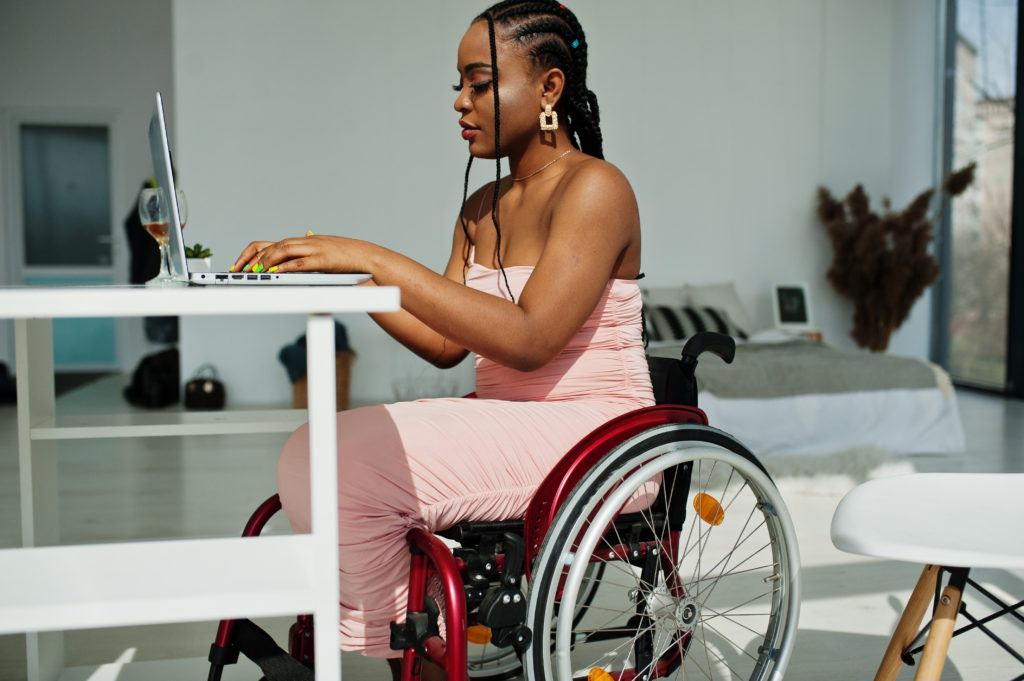 How to Hunt for Disabled-Accessible Apartments in NYC - woman in wheelchair at home working with laptop