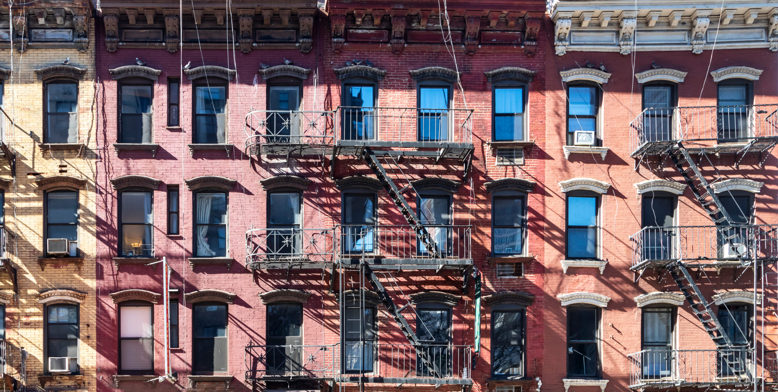 What is a rent-controlled apartment in NYC: Sunlight shining on block of old buildings in the Upper East Side neighborhood in Manhattan New York City