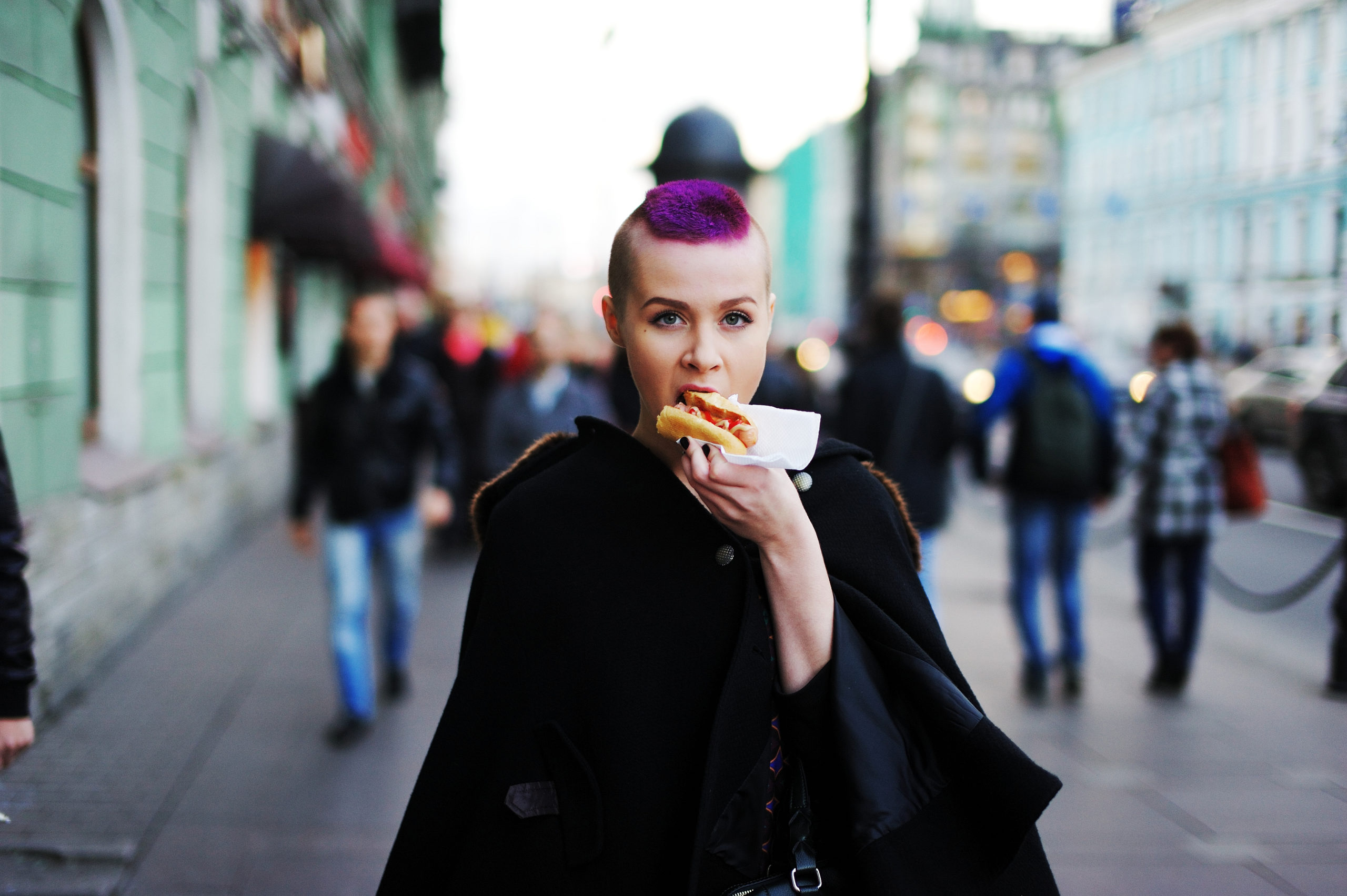 Bona Fide Punk Scene in NYC (Now) - young woman with a purple hair eating a large huge meat hot dog in the city